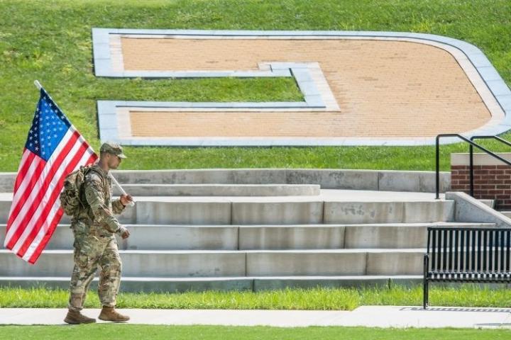 一名士兵手持美国国旗走在张伯伦球场的Power C球场前.